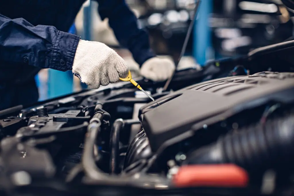 Mechanic checking dipstick to see if car needs oil change